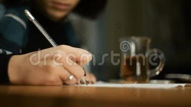 年轻女子坐在户外咖啡馆，秋天，裹着毯子，她在文件上签名，写着一支铅笔